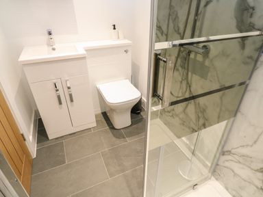 A bathroom with a white sink cabinet a toilet and a glass door shower at Pol View in Gunwalloe near Helston