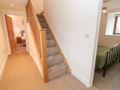 A hallway with carpeted stairs and doors leading to two bedrooms at Pol View in Gunwalloe near Helston