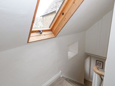 A stairwell with a wooden handrail and a skylight window at Bobbin Cottage in Swanage