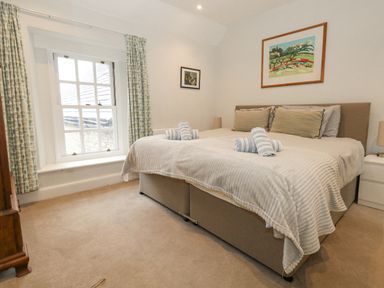 A bedroom with a double bed two rolled towels on the bed and two framed pictures on the walls at Bobbin Cottage in Swanage