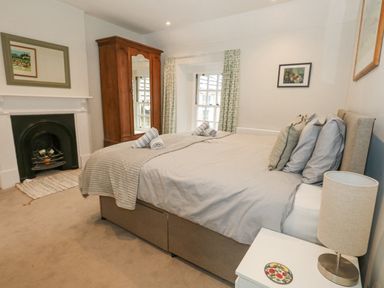 A bedroom with a bed pillows side table lamp fireplace and mirrored wardrobe at Bobbin Cottage in Swanage