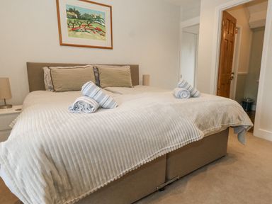 A bedroom with a bed with rolled towels on it and a framed picture on the wall at Bobbin Cottage in Swanage