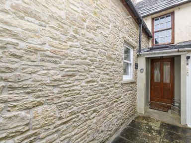 A stone wall with a window and a wooden door at Bobbin Cottage in Swanage