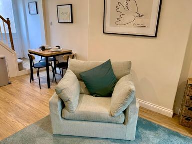 A living room with an armchair and a dining table at Bobbin Cottage in Swanage