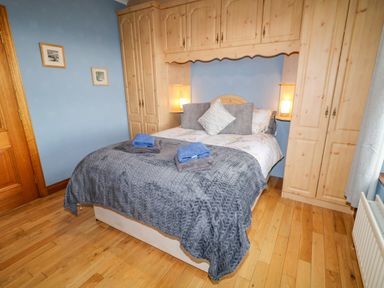 A bedroom with a double bed and built in wooden wardrobes at Braeside Farm House in Cloughmills