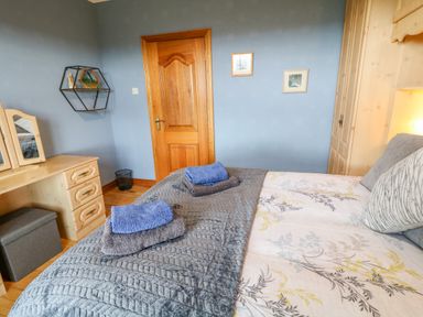 A bedroom with a bed towels on it a wooden door and a dressing table at Braeside Farm House in Cloughmills