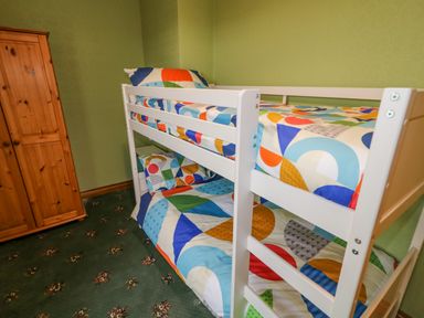 A bedroom with a white bunk bed with colorful bedding and a wooden wardrobe at Braeside Farm House in Cloughmills