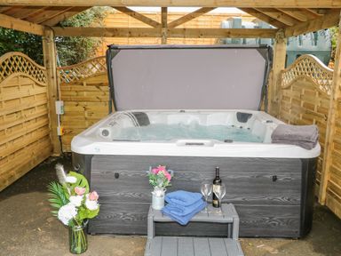 A covered outdoor hot tub with towels flowers and wine glasses at Braeside Farm House in Cloughmills