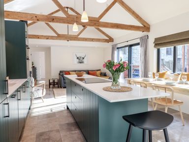 A kitchen and dining area with an island counter and wooden beams at 1 Caddaford Barns in Buckfastleigh