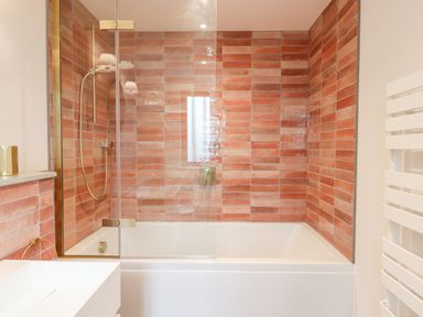 A bathroom with a bathtub and shower with red tiles on the walls at 1 Caddaford Barns in Buckfastleigh