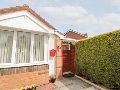 The exterior of a house with a red mailbox near a white window and a hedgerow at Tartaria in Widdrington