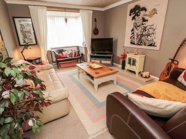 A living room with two sofas a coffee table a television and a window seat at Tartaria in Widdrington