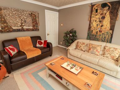A living room with two sofas a coffee table and wall tapestries at Tartaria in Widdrington