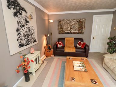 A living room with a brown leather sofa guitar floor lamp and a wooden coffee table at Tartaria in Widdrington