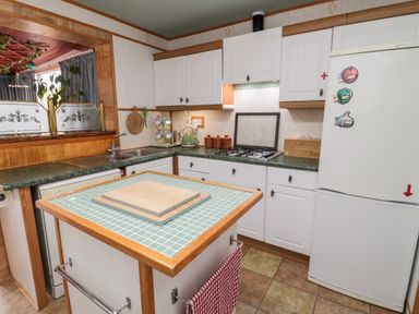 A kitchen with white cabinets green countertops a small island and a double sink at Tartaria in Widdrington
