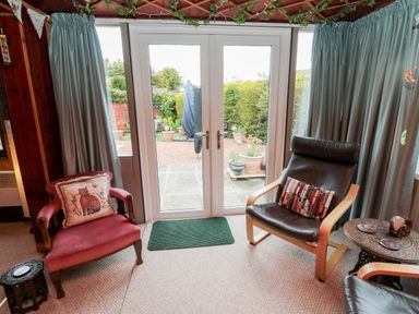 A sitting area with two chairs a small table and glass double doors leading to a garden at Tartaria in Widdrington