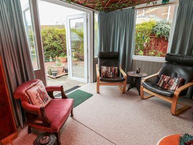 A room with three chairs and a small table next to open glass doors leading outside at Tartaria in Widdrington