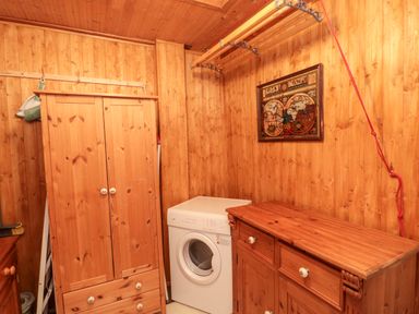 A utility room with wooden cabinets a washing machine and a framed map on the wall at Tartaria in Widdrington
