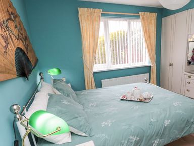 A bedroom with a bed and green lamps beside a window with yellow curtains at Tartaria in Widdrington