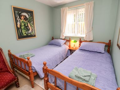 A bedroom with two single beds covered with purple bedspreads and green towels at Tartaria in Widdrington