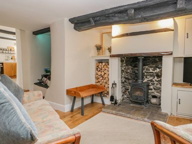 A living room with a fireplace wood stove sofa and a wooden bench at Ashness in Bassenthwaite near Keswick