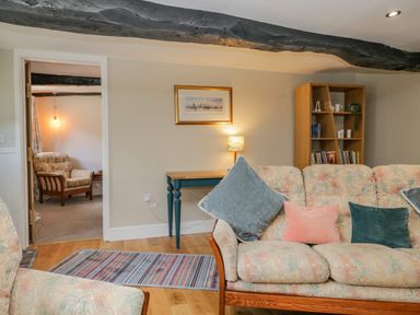 A living room with floral patterned sofas a wooden bookshelf and a blue side table at Ashness Bassenthwaite near Keswick
