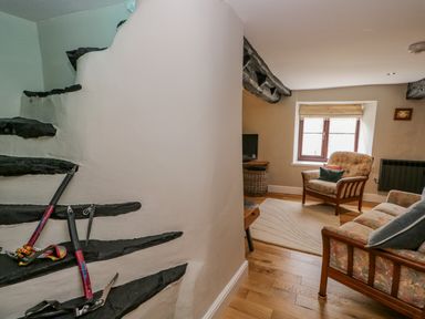 A living room with armchairs and a sofa with floral upholstery and a staircase with black steps at Ashness in Bassenthwaite near Keswick