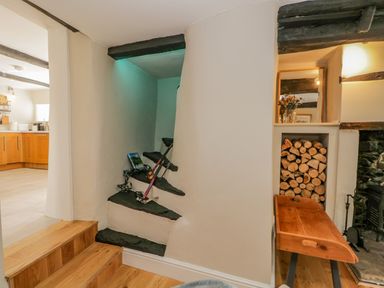 A small staircase with ski equipment and a wooden bench next to a wood stack and a fireplace at Ashness in Bassenthwaite near Keswick