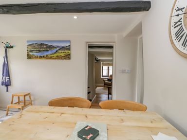 A dining area with a wooden table and chairs looking into a living room with an armchair at Ashness in Bassenthwaite near Keswick