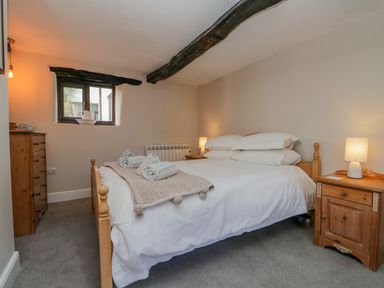 A bedroom with a double bed bedside tables with lamps a window and wooden dresser at Ashness in Bassenthwaite near Keswick