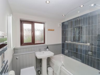 A bathroom with a sink toilet bathtub with glass screen and tiled wall at Ashness in Bassenthwaite near Keswick