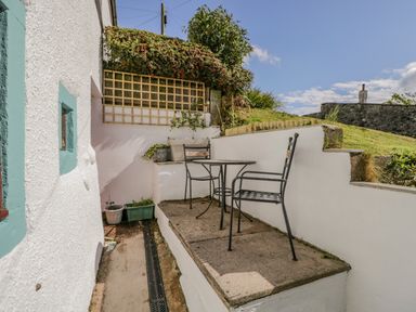 An outdoor patio area with two metal chairs and a table next to a white building with turquoise window frames at Ashness in Bassenthwaite near Keswick