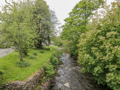 A small river running alongside green grass and trees at Ashness in Bassenthwaite near Keswick