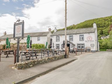 An outdoor seating area with picnic tables and umbrellas outside the Sun Inn in Bassenthwaite near Keswick