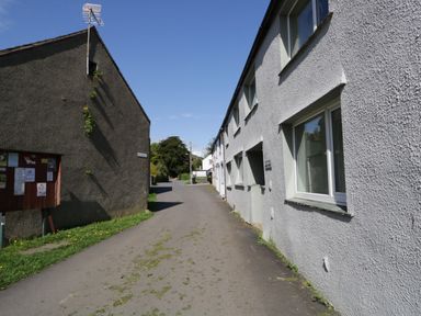 A narrow street between two buildings with windows and a bulletin board on one side at Ashness in Bassenthwaite near Keswick