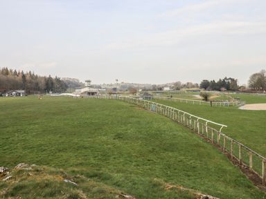 A large grassy horse racing track with fencing and a grandstand in the distance at 1 Tower House in Cartmel