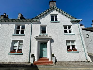 A white house with a blue door and flower boxes under the windows at 1 Tower House in Cartmel