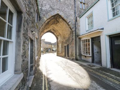 A stone archway over a narrow street with buildings on both sides at 1 Tower House in Cartmel