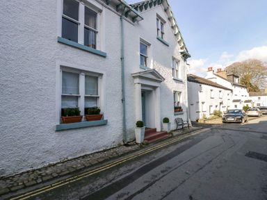 A street with white buildings and parked cars at 1 Tower House in Cartmel