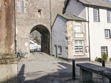 A stone archway over a road next to a building with a sign for an antiquarian bookshop at 1 Tower House in Cartmel