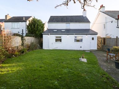 A white two-story house with a lawn and pathway at Disgwylfa in Moelfre