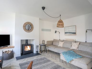 A living room with a fireplace a large sofa and a television at Disgwylfa in Moelfre
