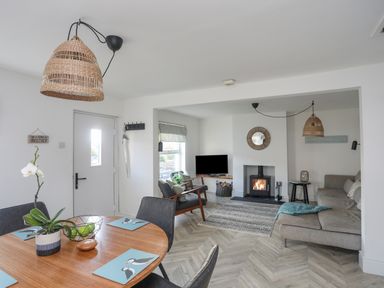 A living and dining area with a round wooden table and chairs a fireplace and a sofa at Disgwylfa in Moelfre
