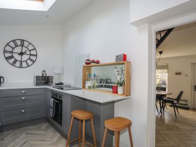A kitchen with grey cabinets and wooden stools at Disgwylfa in Moelfre