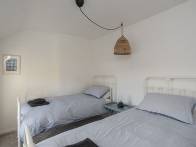 A bedroom with two single beds and a blue side table with a lamp at Disgwylfa in Moelfre