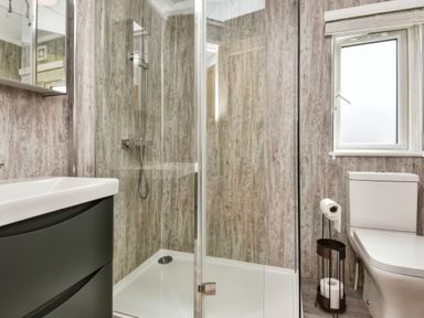 A bathroom with a shower enclosure a sink a toilet and a window at Gerrida Lodge South Lakeland Leisure Village near Tewitfield