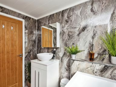 A bathroom with a white sink cabinet a wooden door and plants on a shelf at Gerrida Lodge South Lakeland Leisure Village near Tewitfield
