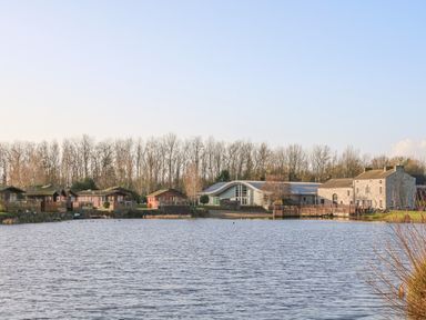 Lake with houses and trees at Gerrida Lodge South Lakeland Leisure Village near Tewitfield