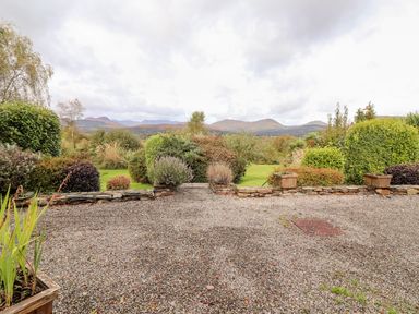 A garden with gravel ground and various shrubs with mountains in the background at Seascape Lodge in Kenmare County Kerry