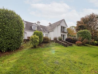 A white house with a slate roof surrounded by shrubs and grass at Seascape Lodge in Kenmare County Kerry